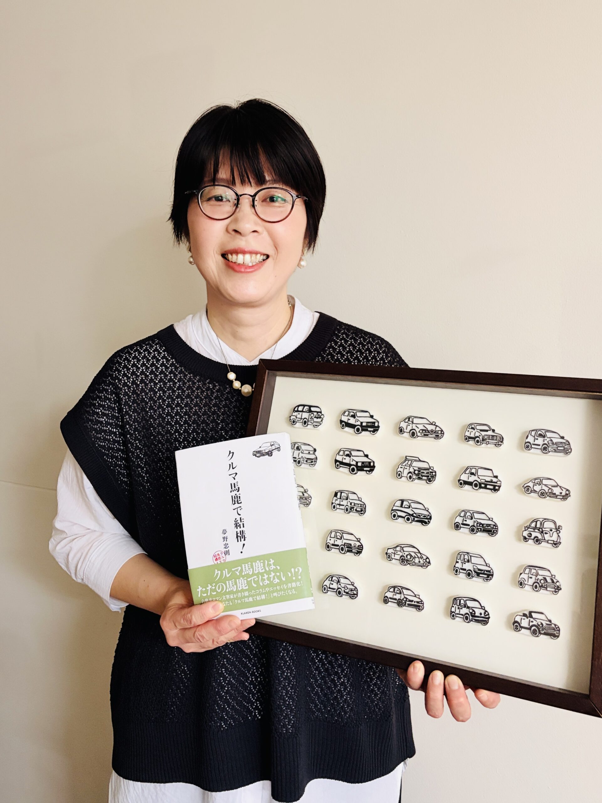 『クルマ馬鹿で結構!』とクルマの消しゴムはんこ作品を持つ松山倫子さん