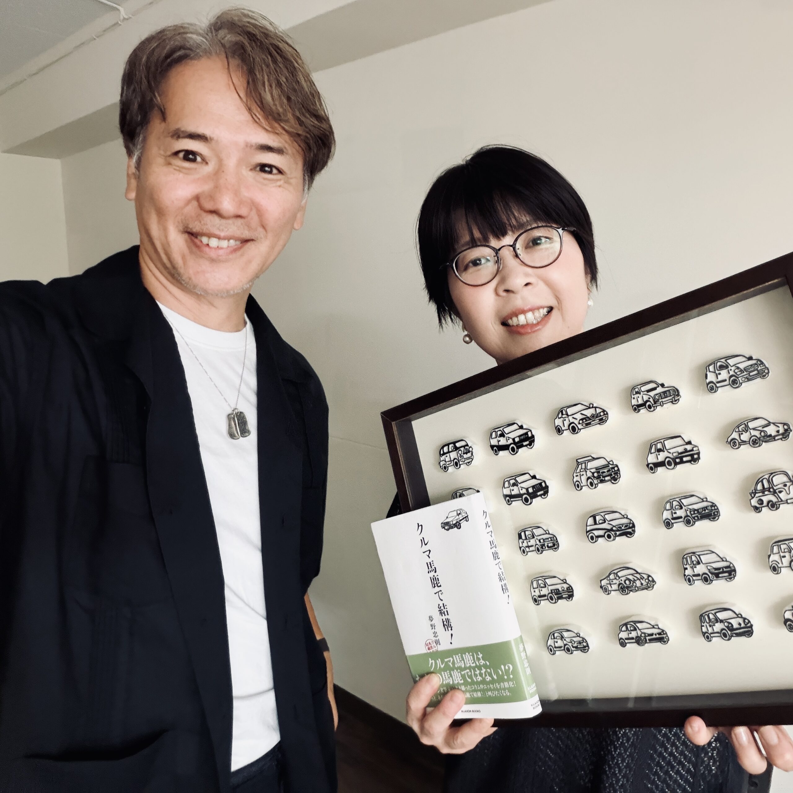 河西啓介と消しゴムはんこ作家・松山倫子さん。『クルマ馬鹿で結構!』とクルマのはんこ作品を手にして
